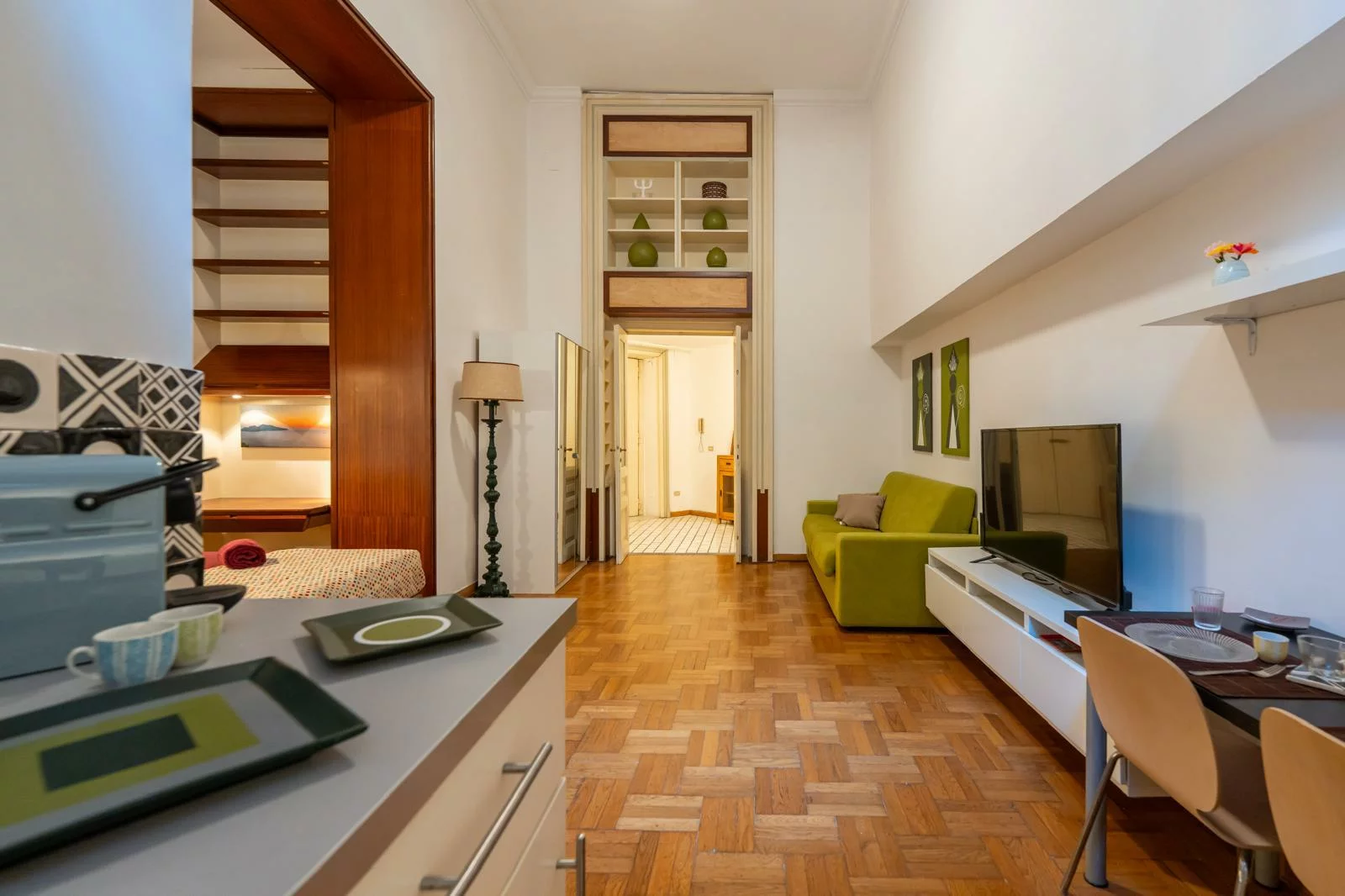 Salotto con divano verde, TV e parquet in legno